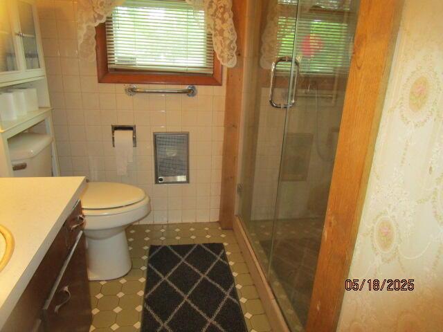 260 W Saint Joseph St, Coloma, MI 49038 - full bathroom featuring a stall shower, vanity, toilet, tile patterned floors, and tile walls