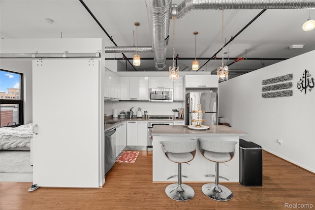 100 N Center St Unit 404, Royal Oak, MI 48067 - kitchen featuring appliances with stainless steel finishes, white cabinets, a kitchen island, wood finished floors, and a towering ceiling