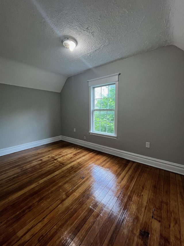 611 New Ave SW, Grand Rapids, MI 49503 - bonus room with lofted ceiling, dark wood-style floors, baseboards, and a textured ceiling