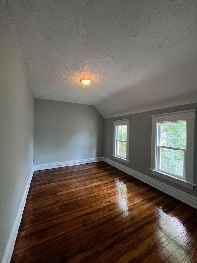 611 New Ave SW, Grand Rapids, MI 49503 - empty room featuring a textured ceiling, dark wood-type flooring, lofted ceiling, and baseboards
