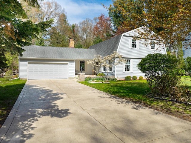 colonial inspired home featuring driveway, an attached garage, a gambrel roof, a front lawn, and a shingled roof