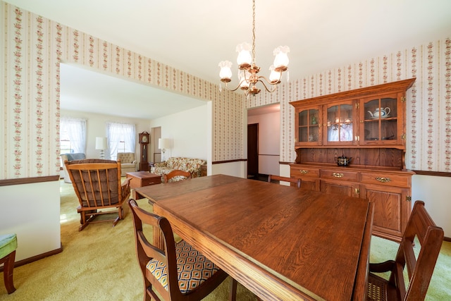 dining area featuring light carpet, wallpapered walls, a chandelier, and baseboards