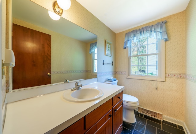 bathroom with wallpapered walls, toilet, and vanity
