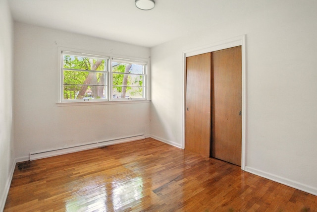 1469 Westwood Dr, Flint, MI 48532 - unfurnished bedroom featuring a baseboard radiator, wood finished floors, a closet, and baseboards
