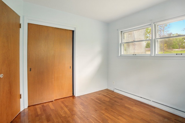 1469 Westwood Dr, Flint, MI 48532 - unfurnished bedroom with baseboard heating, wood finished floors, baseboards, and a closet