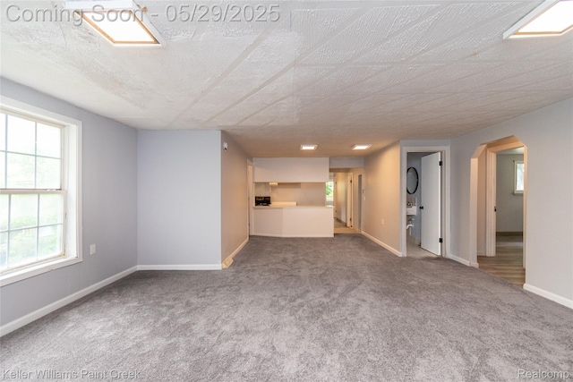 72 N Astor St, Pontiac, MI 48342 - unfurnished living room with carpet, arched walkways, and baseboards