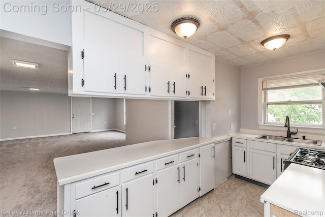72 N Astor St, Pontiac, MI 48342 - kitchen featuring a sink, white cabinets, light countertops, range with gas stovetop, and light colored carpet