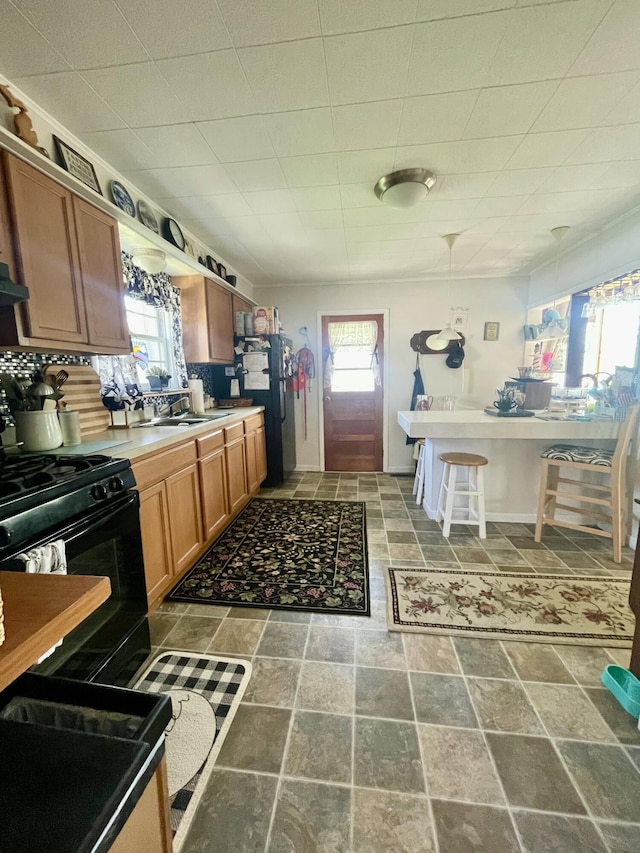 404 W Court St, Ludington, MI 49431 - kitchen featuring black range with gas cooktop, plenty of natural light, stone finish flooring, and brown cabinets