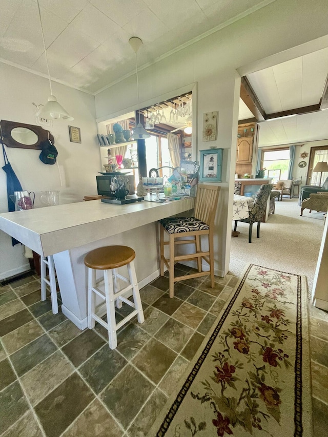 404 W Court St, Ludington, MI 49431 - kitchen featuring ornamental molding, stone tile flooring, a kitchen bar, and a peninsula