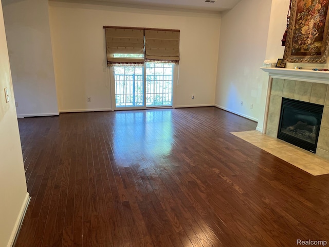 2065 Pinecroft Dr Unit 201, Canton, MI 48188 - unfurnished living room featuring a tiled fireplace, hardwood / wood-style floors, and baseboards