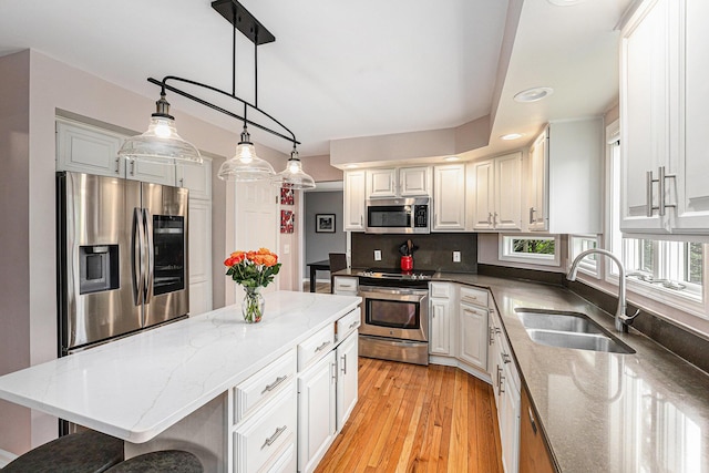 1817 High Pointe Ln, Ann Arbor, MI 48108 - kitchen featuring appliances with stainless steel finishes, a sink, a breakfast bar, light wood-type flooring, and light stone counters