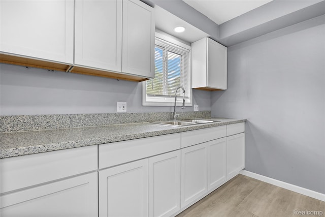 3907 Bayhan St, Inkster, MI 48141 - kitchen featuring a sink, light wood-type flooring, white cabinetry, baseboards, and light stone countertops