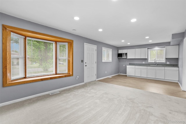 3907 Bayhan St, Inkster, MI 48141 - kitchen featuring light carpet, stainless steel microwave, baseboards, white cabinets, and recessed lighting
