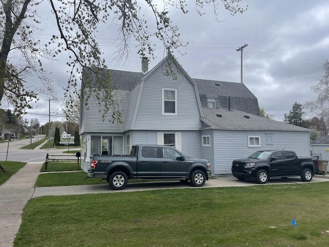 9 N Michigan Ave, Shelby, MI 49455 - view of side of home featuring a shingled roof, a lawn, a chimney, and a gambrel roof