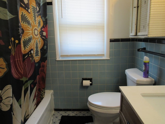 full bathroom with toilet, tile patterned floors, vanity, tile walls, and wainscoting