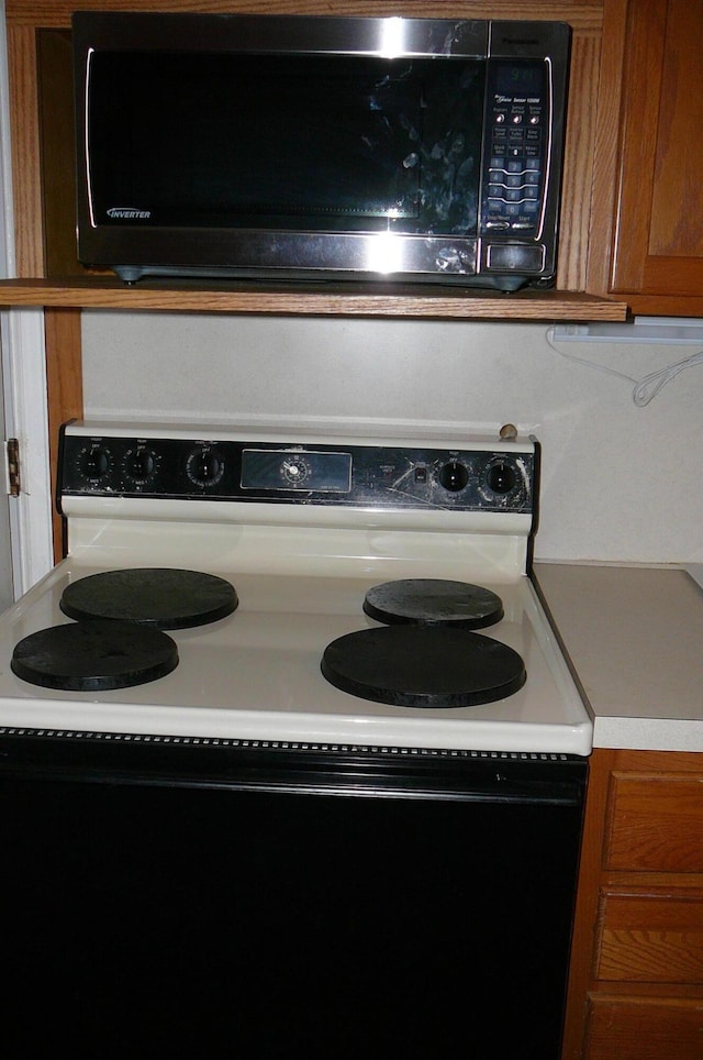 466 Salem Dr, Jonesville, MI 49250 - kitchen view of electric range, black microwave, brown cabinetry, and light countertops