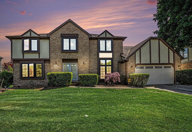 41925 Waterwheel Rd, Northville, MI 48168 - tudor home with a garage, a front yard, driveway, and brick siding