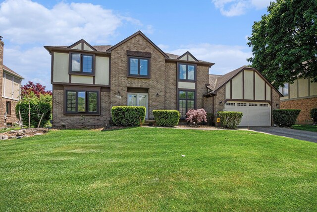 41925 Waterwheel Rd, Northville, MI 48168 - tudor-style house featuring brick siding, driveway, a front lawn, and an attached garage