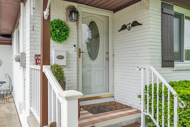 entrance to property with a porch and brick siding