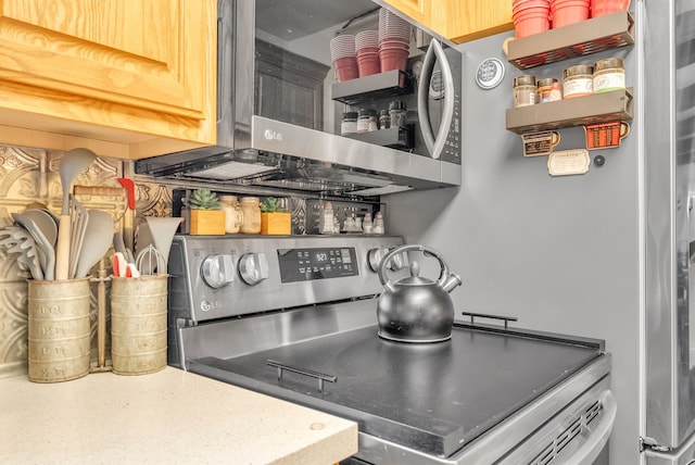 kitchen view of stainless steel appliances, open shelves, and light countertops