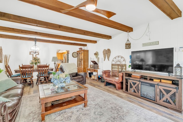 living area with wood finished floors, beam ceiling, a chandelier, and a ceiling fan