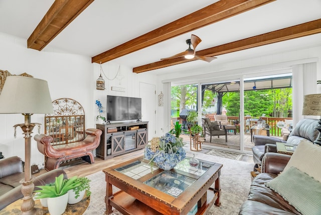 living area with a ceiling fan, beamed ceiling, and wood finished floors