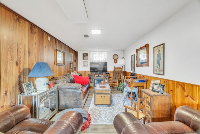 living area featuring wood walls, wood finished floors, wainscoting, and attic access