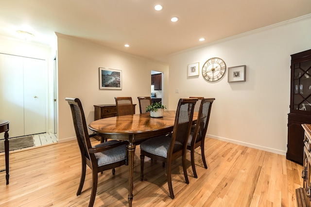 dining space with ornamental molding, recessed lighting, light wood-style flooring, and baseboards