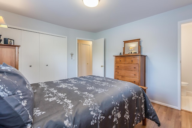 bedroom with a closet, wood finished floors, and baseboards