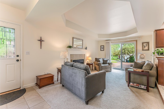 living room featuring a tray ceiling, a tile fireplace, and light tile patterned flooring