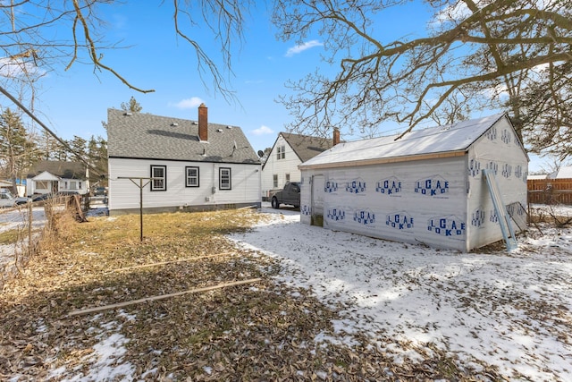 9069 Pierson St, Detroit, MI 48228 - snow covered rear of property featuring an outdoor structure, a chimney, and a garage