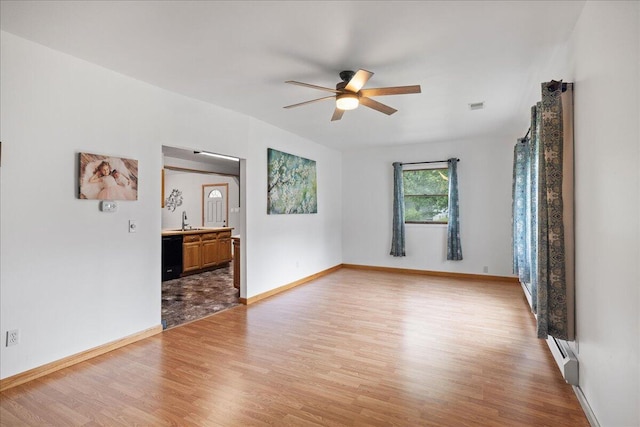 45 E Beech St, Fruitport, MI 49415 - spare room with light wood-style flooring, a ceiling fan, baseboards, baseboard heating, and a sink