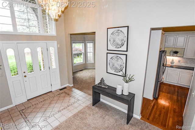 8342 Islandview Ct, Brighton, MI 48114 - carpeted entryway featuring a high ceiling, a chandelier, baseboards, and tile patterned flooring