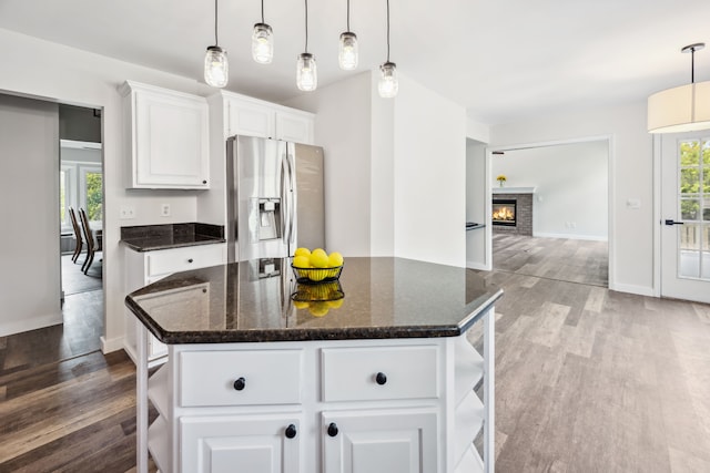 8148 Orchardview Dr, Washington, MI 48095 - kitchen with stainless steel fridge, wood finished floors, white cabinetry, and dark stone counters