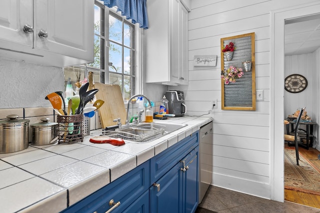 8911 Manor Ave, Allen Park, MI 48101 - kitchen with a sink, blue cabinetry, tile counters, dishwasher, and wooden walls