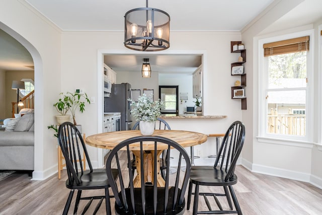5915 S Pipestone Rd, Eau Claire, MI 49111 - dining room featuring light wood-style flooring, baseboards, a chandelier, arched walkways, and ornamental molding