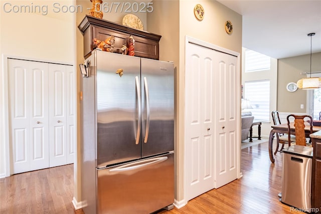 791 Glen Meadows Dr, South Lyon, MI 48178 - kitchen with freestanding refrigerator, light wood-style flooring, dark brown cabinetry, and hanging light fixtures