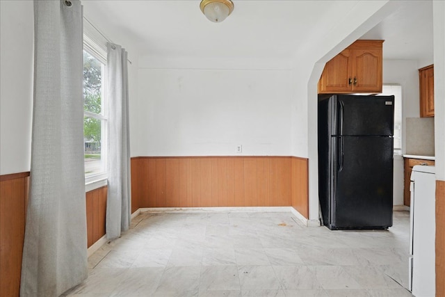 21803 Brittany Ave, Eastpointe, MI 48021 - kitchen with freestanding refrigerator, wainscoting, wooden walls, brown cabinetry, and baseboards