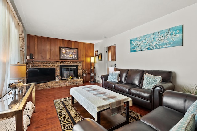 living room featuring a brick fireplace, wood finished floors, and wooden walls