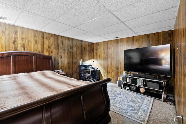 bedroom featuring carpet floors, a paneled ceiling, and wood walls