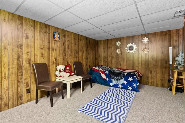 bedroom with carpet flooring, wooden walls, and a paneled ceiling