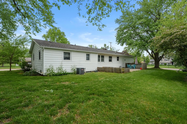 rear view of property with central AC and a yard