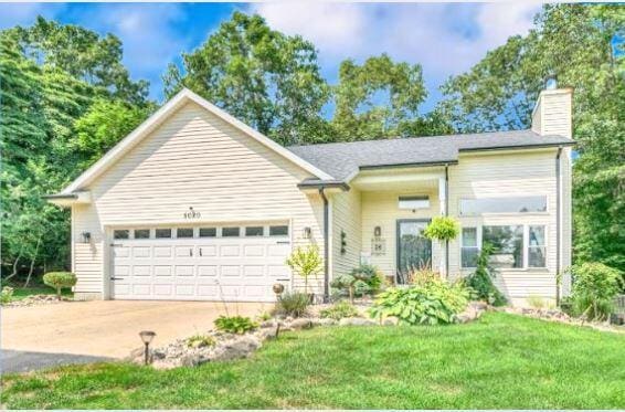 ranch-style house featuring a chimney, a garage, driveway, and a front yard