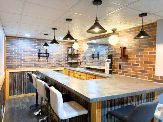 bar area featuring pendant lighting, dark wood-style flooring, and brick wall
