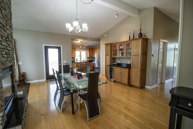 13496 S Horrell Rd, Fenton, MI 48430 - dining room featuring beverage cooler, a chandelier, a fireplace, beam ceiling, and light wood-type flooring