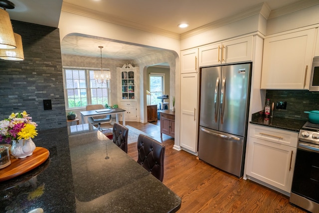 2366 Grange Rd, Trenton, MI 48183 - kitchen with stainless steel appliances, arched walkways, dark wood-style floors, crown molding, and backsplash