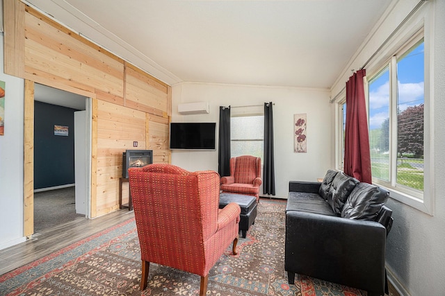living area featuring plenty of natural light, crown molding, wooden walls, an AC wall unit, and wood finished floors