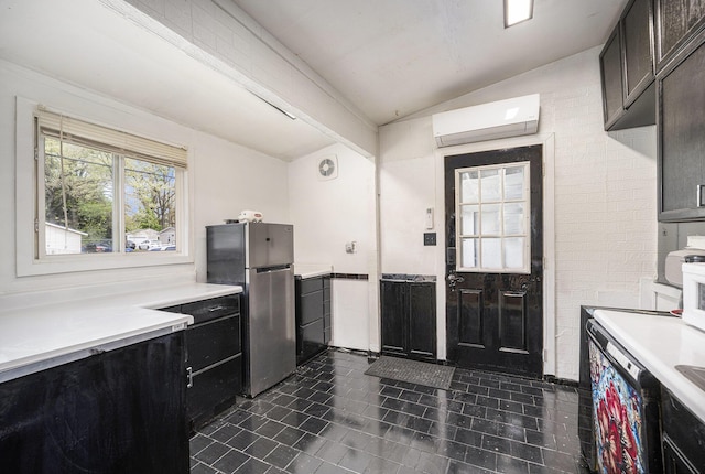 kitchen featuring a wall mounted air conditioner, freestanding refrigerator, lofted ceiling, dark tile patterned floors, and light countertops