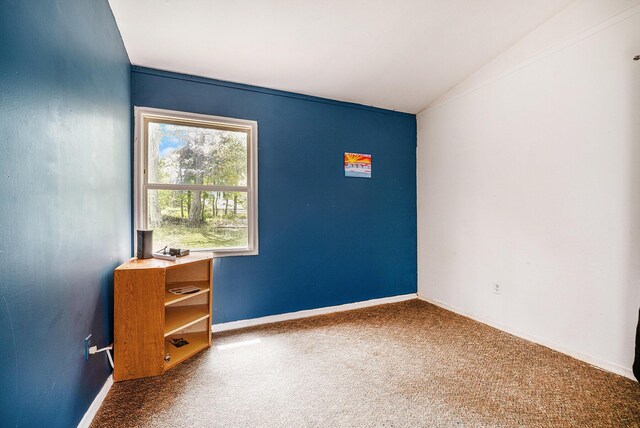 unfurnished room featuring carpet flooring, vaulted ceiling, and baseboards