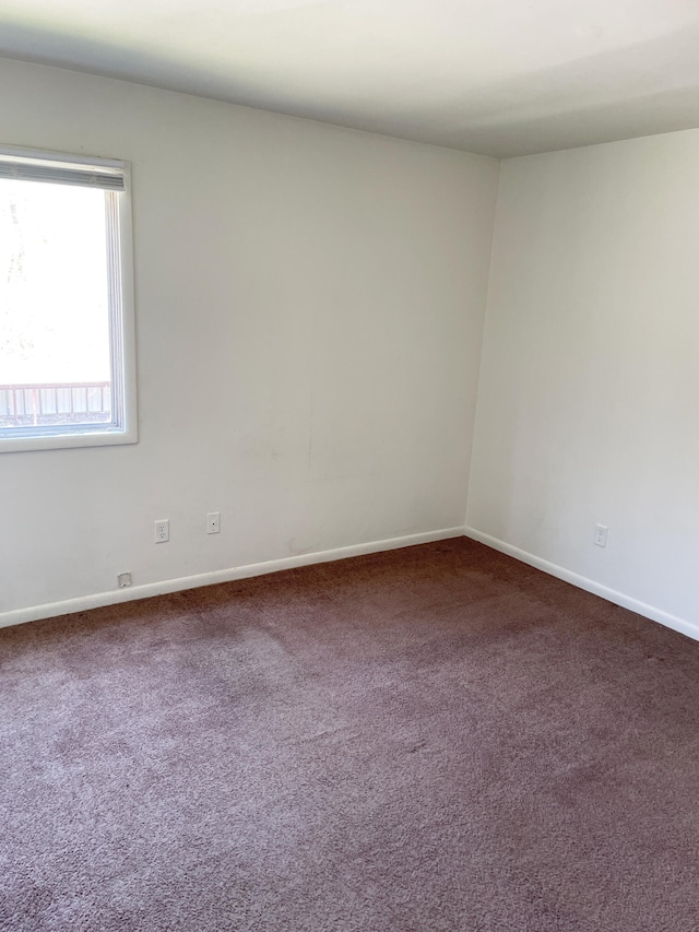 unfurnished room with dark carpet and baseboards